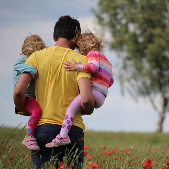 SOLOMÜTTER Info-Kachel: Bild Vater von hinten mit zwei Kleinkindern auf dem Arm